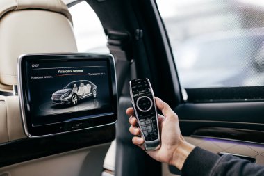 Bir arabada multimedya uzaktan kumanda tutan bir adam 