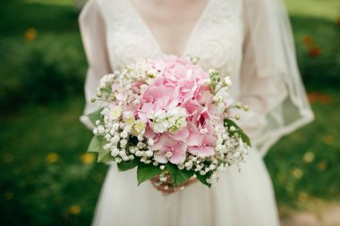 Gelin çiçeğini pembe ortancayla tutuyor.