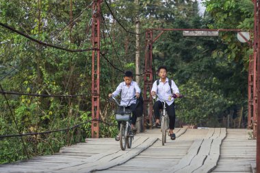 Vang Vieng, Laos - 7 Aralık 2012: Tahta Köprü 'de okuldan dönen kimliği belirsiz genç çocuk.