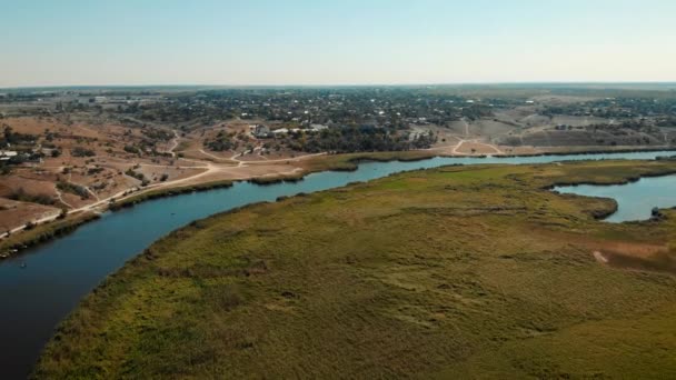 Tournage cinématographique d'une grande rivière avec de l'eau bleue et un grand village autour — Video