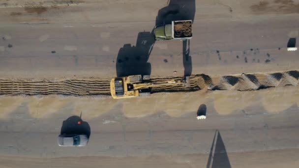 Grote rupsgraafmachine graaft sleuf tussen twee rijstroken snelweg en vintage vrachtwagen rijdt langs de weg — Stockvideo