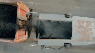 Eski asfalt katmanını değirmen ve öğütme makinesiyle kapatıyoruz. Yol yapımı işe yarıyor. Paver pudralanmış kapağı kamyona doldurur