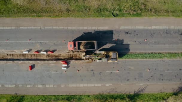 Luchtfoto van de laadbak van de graafmachine met de grond op bouwplaats op de weg — Stockvideo