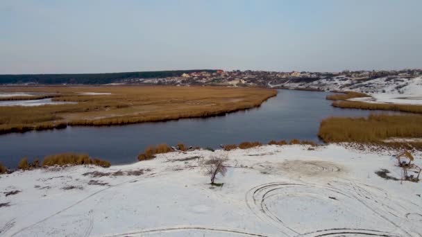 Rio azul no inverno com juncos secos e neve na costa — Vídeo de Stock
