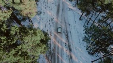 Karlı kış ormanı yolunun üzerinde beyaz arabalı İHA uçuşu