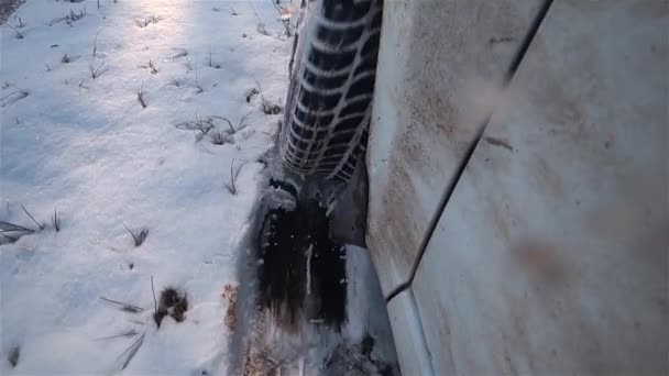 Sporco bianco ruota auto spin e sputare fino pesante neve bagnata come conducente cerca di guidare fuori strada in difficili condizioni invernali e palude schizza obiettivo della fotocamera — Video Stock