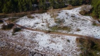 Mavi dörtlü bisiklet. Kışın karlı, ormanın yakınındaki toprak kum yolunda giden iki atlı.