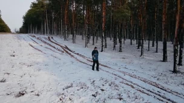 Man tourist in hot wearing fast walking with backpack through dense pine forest by snow at winter — Stock Video