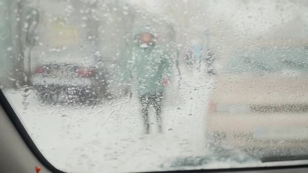 Blick von der Windschutzscheibe des Autos mit Scheibenwischern im Winter auf verschwommene Menschen Silhouetten zu Fuß — Stockvideo