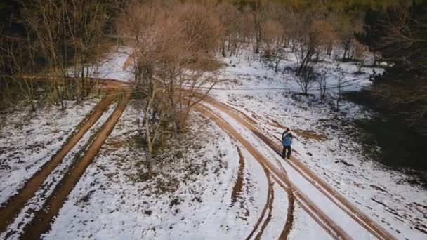 Man vandrare med ryggsäck promenader med snö nära stora träd utan blad på vintern — Stockvideo