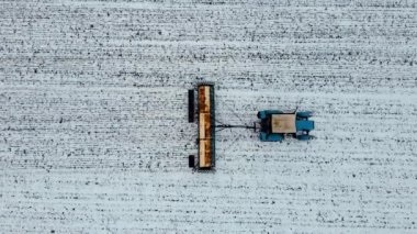 Geniş ve yakın çekim çeşitliliği, tarımsal birimle birlikte traktörün kışın tarlayı ekip karlı toprağa gübre ektiğini gösteriyor.