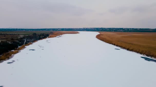 寒い冬の天候では、空中ビューで雪の下で凍結川。氷水の上を飛ぶプロのカメラ — ストック動画