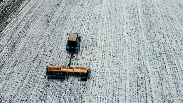 Bredt og tett utvalg av bilder som viser gjødslende jord og gjør seg klar til våren ved hjelp av traktor som arbeider på agronomisk felt med lag av snø om vinteren – stockvideo