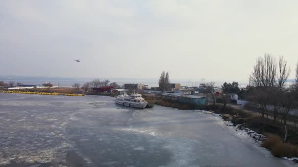 Пассажирский вертолет пролетает над кораблем удовольствия в замерзшей гавани или порту с тающим льдом — стоковое видео