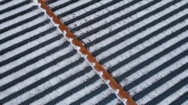 Вид сверху солнечной электростанции с возобновляемыми элементами зимой стоит в заснеженном поле — стоковое видео
