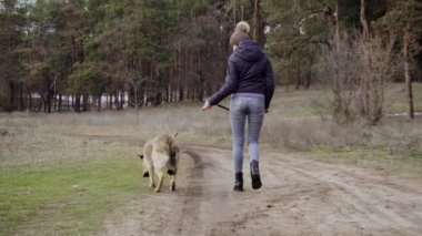 Sıcak giysiler içinde genç ve tatlı bir kadın kış ormanlarında çoban köpeğiyle dışarıda yürüyor. Koronavirüs salgını yüzünden herkesin sosyal mesafeye ihtiyacı var.