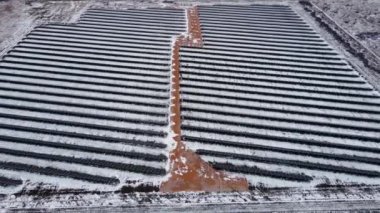 Güneş panellerinin inanılmaz hava manzarası kışın yeşil enerji üretimi için karlı arazilerde sıra sıra diziliyor.