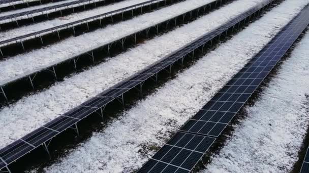 Erstaunliche Nahaufnahme von Sonnenkollektoren stehen in Reihen in schneebedeckten Feldern für die Produktion grüner Energie in der Winterlandschaft — Stockvideo