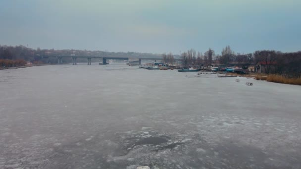 Zmrazená řeka s tavícím ledem v zimě a kamenný most pro automobilový provoz — Stock video