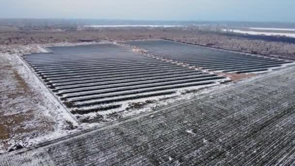 Aerial top view of new solar farm standing in rows of modern photovoltaic panels in snowy land — Stok video