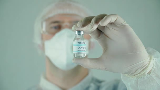 Doctor microbiologist virologist researcher scientist in laboratory in protective mask and gloves holding ampoule with vaccine injection — Stock Video