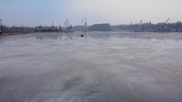 Jég olvadása folyami vízen elhagyatott kikötőben darukkal és rakpartokkal — Stock videók
