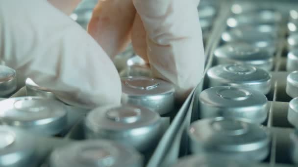 Крупним планом медичний працівник в захисних рукавичках бере флакони або пляшки з коронавірусною вакциною з коробки, розробляє нові ліки — стокове відео