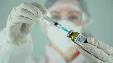 Doktor ya da hemşire şırıngayı iğneyle dolduruyor. Aşıyı laboratuarda sıvı ilaçla tutuyor.