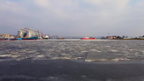 Drohnenaufnahmen von Frachtterminals auf schmelzendem Eis mit Schiffen und Hafenkränen auf Pier und Getreidelagern — Stockvideo