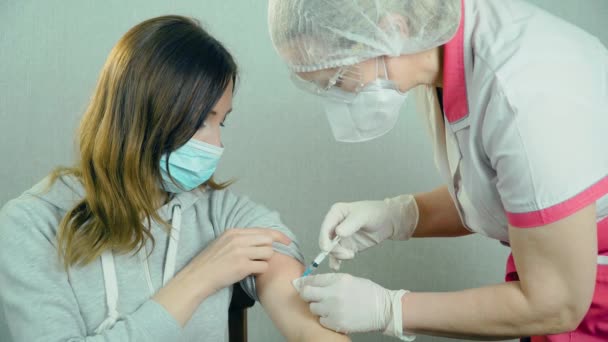 Mikrobiolog lub pracownik medyczny w rękawiczkach chirurgicznych wykonujący wstrzyknięcie szczepionki przeciw koronawirusowi dla pacjentek w szpitalu — Wideo stockowe