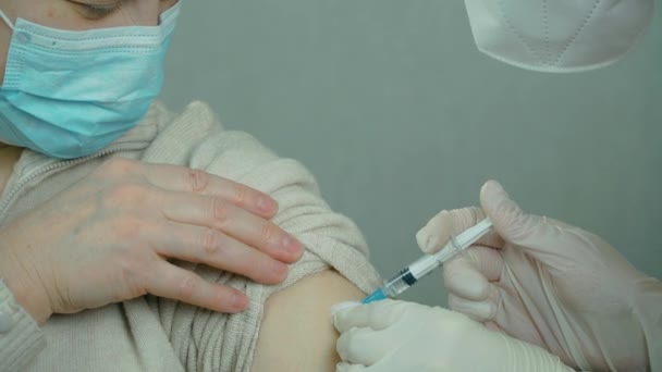 Close up medical nurse or doctor hand with surgical gloves making injection of anti coronavirus vaccine for patient in hospital — Stock Video