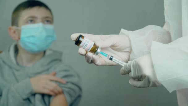 Hastanedeki genç bir çocuğun arka planında iğne ve ampulle tıbbi aşı ekipmanları var. — Stok video