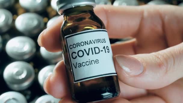 Жінка тримає потенційну вакцину проти коронавірусу в стерильному флаконі або пляшці з аптечними препаратами — стокове відео