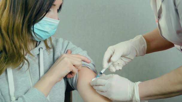 Güvenlik eldivenleri ve koruyucu maske takan tıp hemşiresi sağlık kliniğindeki kadın hastaya aşı yapıyor. — Stok video