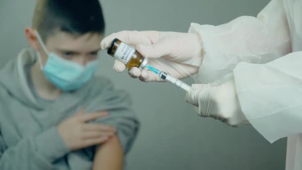 Médico con la jeringa de relleno de mascarilla facial con la vacuna moderna biotech en el fondo del paciente adolescente — Vídeos de Stock
