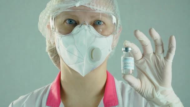 Женщина-медсестра в защитной одежде держит медицинскую трубку с образцами вакцины — стоковое видео