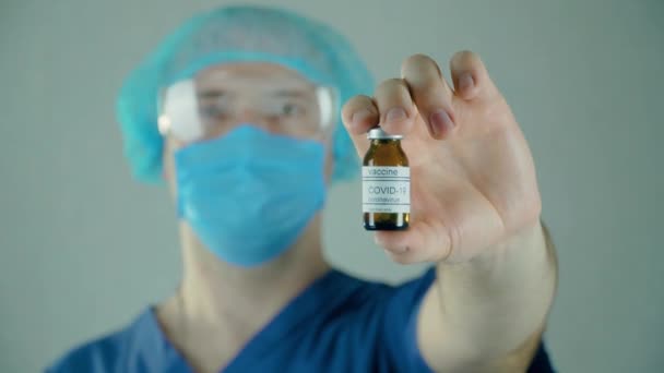Männlicher Wissenschaftler hält Ampulle mit Anti-Coronavirus-Impfstoff in der Hand, neue Medikamente werden entwickelt — Stockvideo