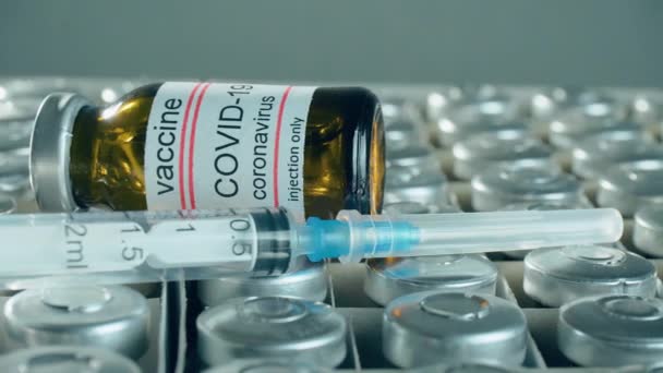 Medicinska injektionsflaskor och sprutor med vaccin mot koronavirus eller andra farmaceutiska specialiteter på full kartong — Stockvideo
