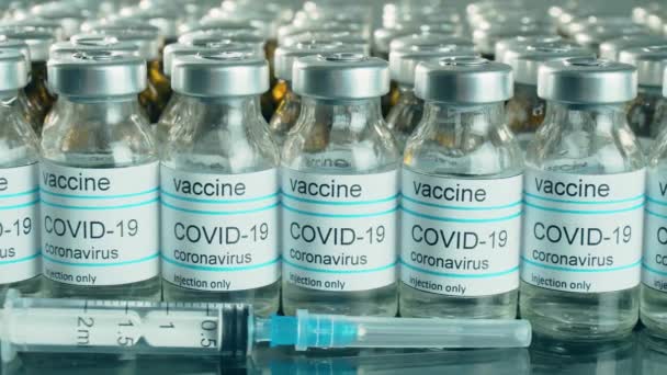 Coronavirus vaccine bottles or vials with syringe in pharmaceutical industry — Stock Video