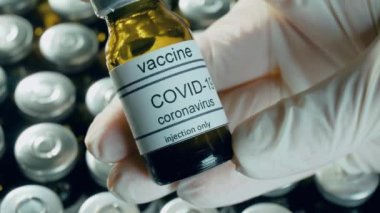 Koronavirüs aşısı şişesinde dünya çapında salgın hastalıklara karşı ilaç şişelerinde ilaç içeren koruyucu eldivenler tutan tıp virologu teslim etti.