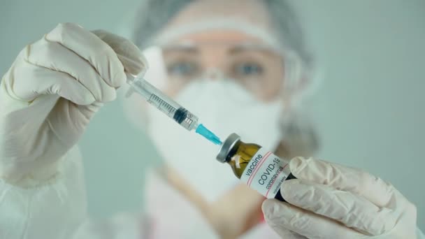 Medische arts die injectiespuit uit injectieflacon vult met een vaccin tegen coronavirus of medicatie in het laboratorium — Stockvideo