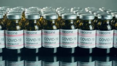 Coronavirus aşısı laboratuvar masa aynası arka planına yakın çekim tüplerinde. Dünya çapında salgına karşı ilaç