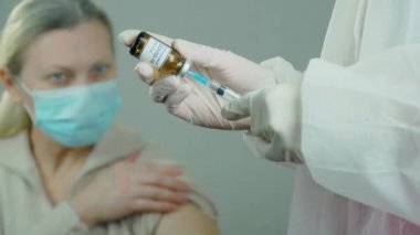 Koruyucu eldiven maskeli tıbbi laboratuvar çalışanı hastaneye anti koronavirüs aşısı ile ampul veya şişe tanıtmaya hazır.