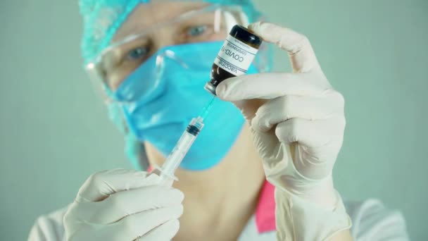 Close-up medisch onderzoeker met gezichtsmasker spuit vullen met biontech moderna vaccin — Stockvideo
