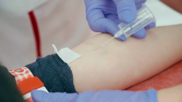 Naald doorboort patiëntenhuid van dichtbij. Proces van het selecteren of nemen van veneuze bloed uit ader met behulp van spuit met buis voor gezondheidsonderzoek. — Stockvideo