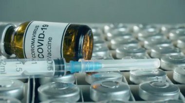 İllüstrasyon uyuşturucu geliştirme süreci, koronavirüs aşısı dolu metal kapaklı şişeler veya şişeler ve iğneli şırınga