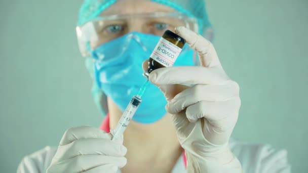Medische onderzoeker met gezichtsmasker die spuit vult met biontech moderna vaccin — Stockvideo