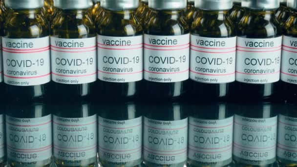 Filas de viales o ampollas con vacuna contra el coronavirus o medicamentos inyectables reflejados en la mesa del espejo — Vídeos de Stock