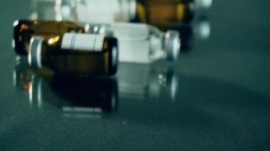 İllüstrasyon uyuşturucu geliştirme süreci, metal kapaklı şişeler veya şişeler aynalı masada yuvarlanan koronavirüs aşısı