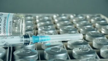 Şişelerde Coronavirus aşısı ve kutulara yakın çekimde şırınga. Dünya çapında salgına karşı ilaç